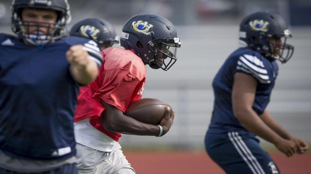 William Chrisman quarterback James Bailey runs the ball between a couple of blockers during a recent practice.