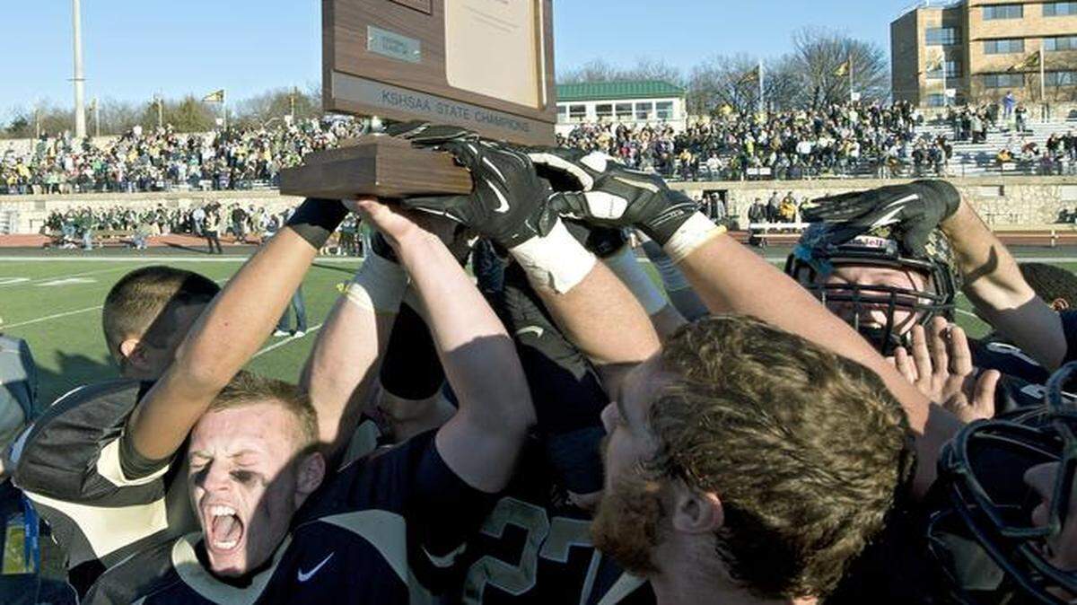 Blue Valley’s players are looking to add a Kansas 6A state trophy to the 5A hardware they won last season.<252><137>Blue Valley's quarterback Logan Brettell (12), left, celebrates with teammates after holding on for a 27-26 win over Salina South during Saturday's Kansas State 5A championship football game on November 30, 2013, in Emporia, Kan.<252><137>
