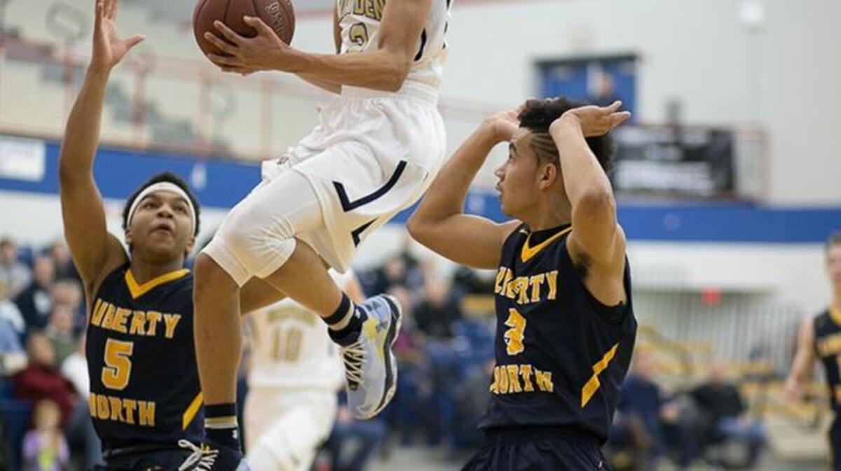 Zach Harvey of Topeka Hayden flies between Macaleb Hughes (left) and Nick Coleman of Liberty North on his way to the basket. Harvey scored 24 points in Hayden’s 62-51 victory.