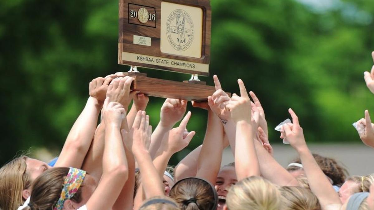 Shawnee Mission West team members celebrated by hoisting the trophy following Sunday’s Kansas Class 6A girls soccer state championship game against Blue Valley West in Junction City, Kan.