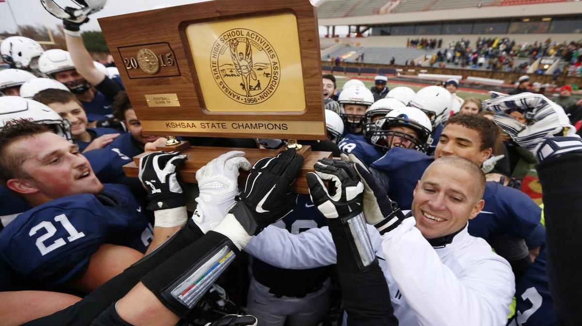 Head coach Joel Applebee (lower right) and his Mill Valley High School football players celebrate their Kansas Class 5A football state championship after a 35-14 victory over Bishop Carroll on Saturday.