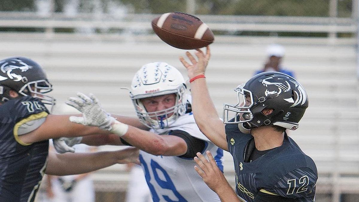 Rockhurst High School’s Carter Selzer (center) pressured Raymore-Peculiar’s Grant Ardito as Ardito attempted to throw a pass during Friday night’s football game at Raymore-Peculiar.
