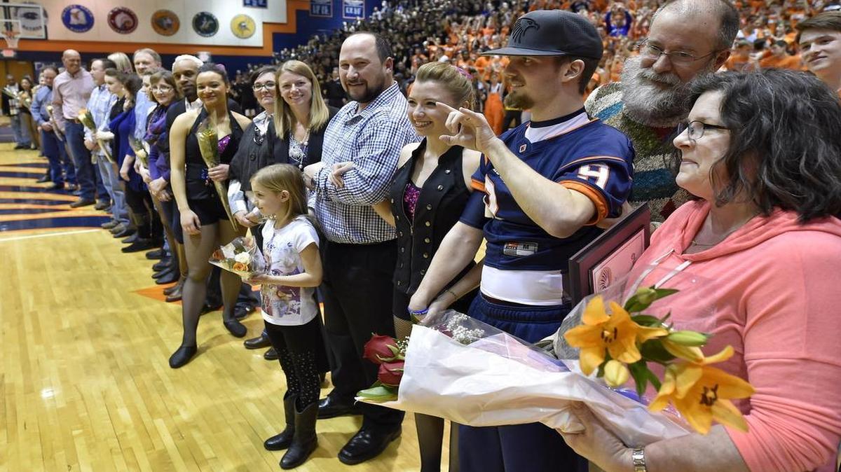 
James McGinnis (center), who suffered a traumatic head injury during the high school football season, was honored during Olathe East’s Senior Night festivities during the basketball season. McGinnis was accompanied by his parents, Patrick and Susan (far right), and his girlfriend, Caitlin Gosik, who had a firm hold on his hand.
