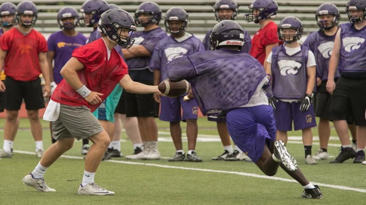 Blue Springs quarterback Chase Donohoe, left, hands off the ball during a recent practice.