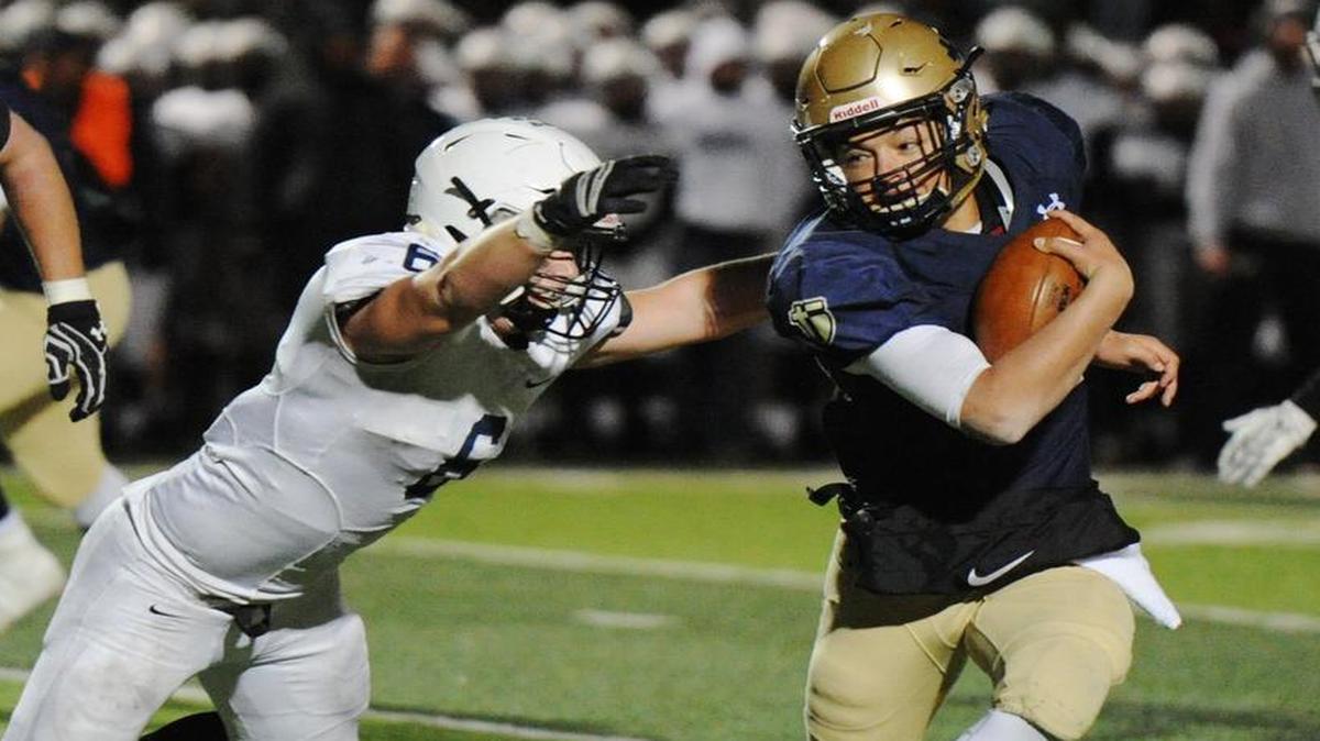 Mill Valley’s Josh Winscott tried to haul in St. Thomas Aquinas quarterback Will Swanson (right) during the Kansas Class 5A semifinals game on Friday night at Saint Thomas Aquinas.
