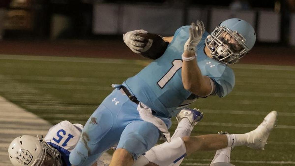 Milton Braasch II of Shawnee Mission East was brought down by Chris Castrop and Matt O’Keefe of Rockhurst during the Hawklets victory last Friday.