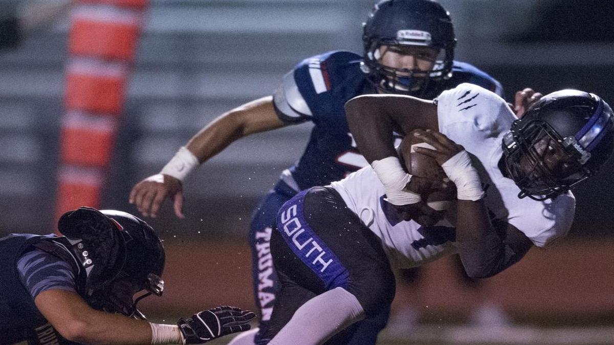 
Emanuel Butler (with football) of Park Hill South looked for running room around Truman defenders Phillip Woolsey (No. 10) and Juan Flores during the fourth quarter of their game on Friday night at William Chrisman High School. Truman edged the Panthers in the game, 27-21.

