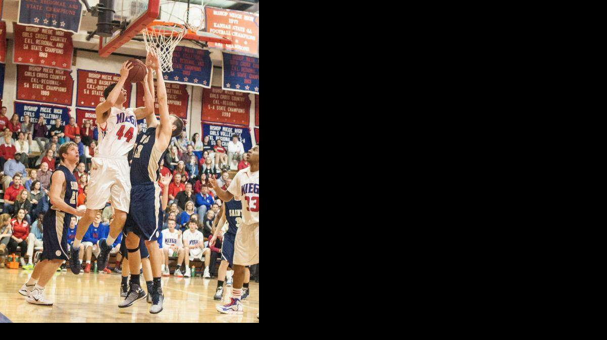 
The Stags’ Carson Mulvey tries to get a shot off over the Saints’ Adam Kutney during the boys game Friday at Bishop Miege. 
