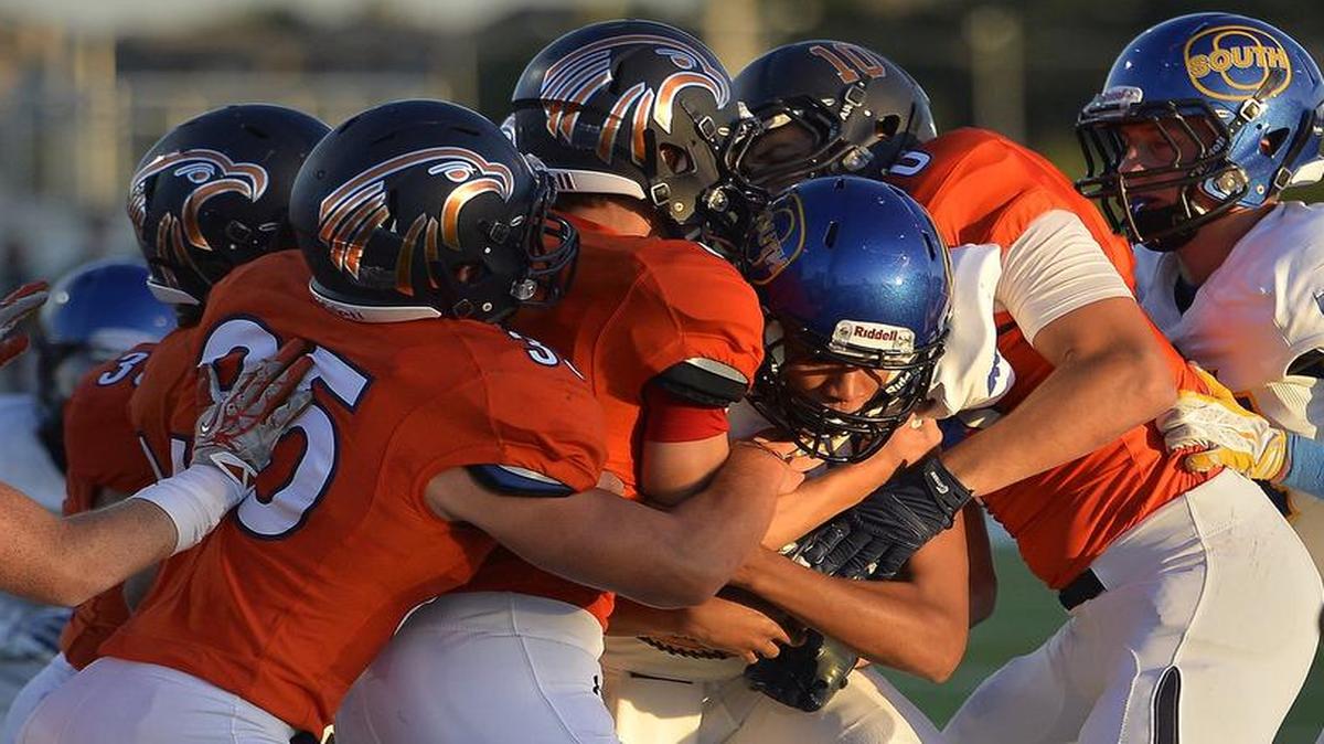 
It took several Olathe East players (in orange) to bring down Olathe South quarterback Andres Glenn near the goal line during the first quarter of their game Friday night.
