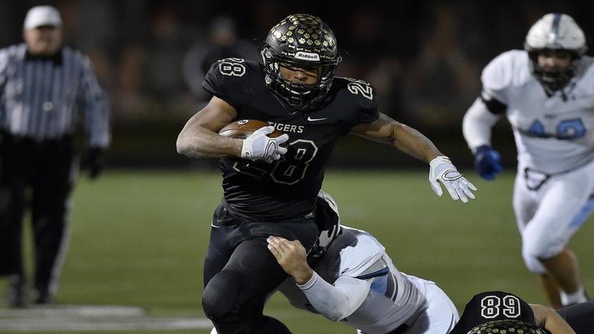Blue Valley’s William Evans got a fourth-quarter first down as Shawnee Mission East’s PJ Spencer tried to bring him down in Friday night’s game at Blue Valley.