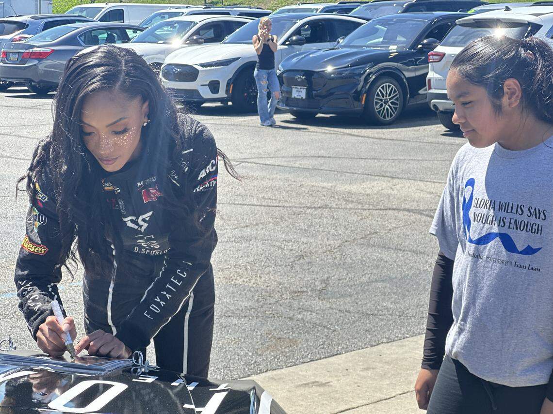Stock car driver Dystany Spurlock signs autographs for Gloria Willis Middle School students at Victory Ford in Kansas City, Kansas.