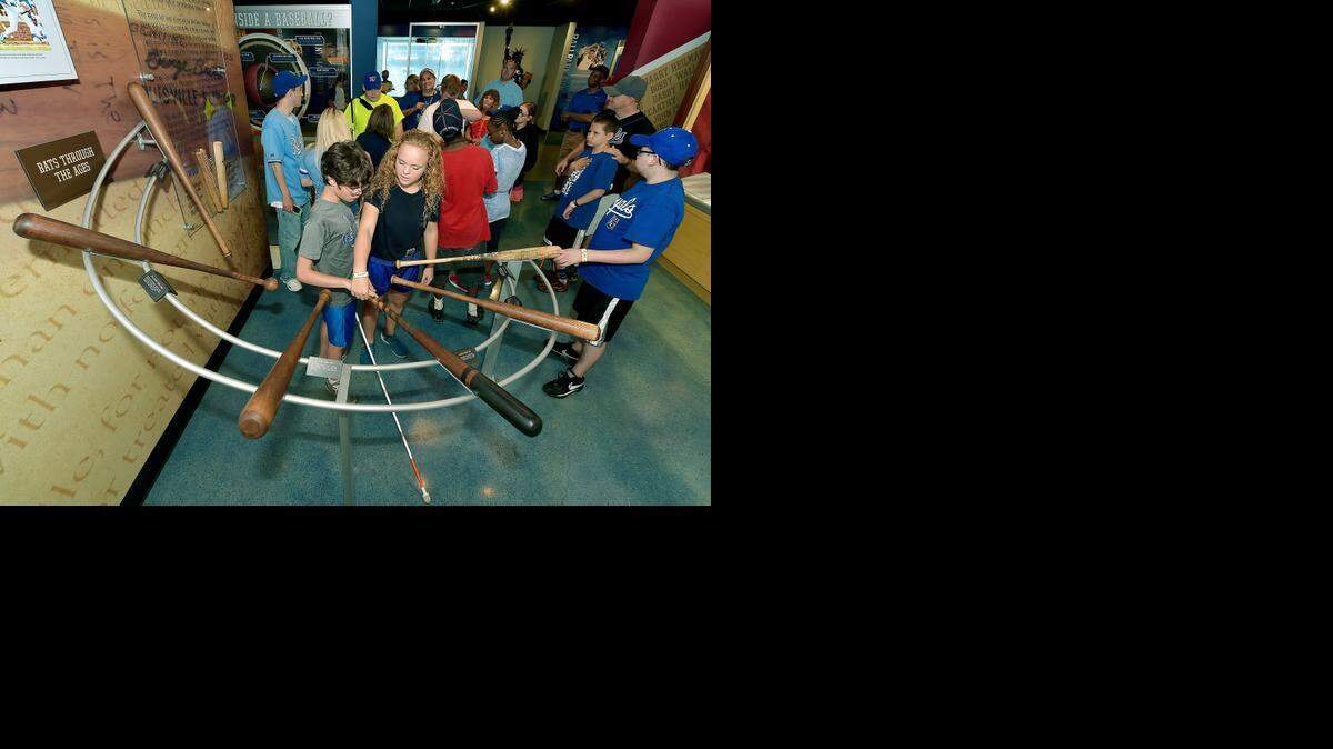 
Hannah Berry, a volunteer at Alphapointe guides the hand of Derek Trischler, who has vision loss, along the handle of a bat during a tour of the Royals Hall of Fame before Tuesday's baseball game against the Los Angeles Dodgers at Kauffman Stadium.
