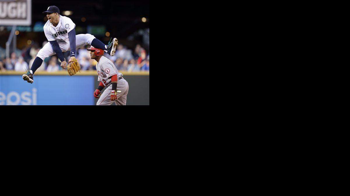 
Seattle Mariners shortstop Brad Miller looked away after missing a catch on a leap in front of Los Angeles Angels' Erick Aybar at second base in the second inning of a baseball game May 27, 2014, in Seattle. 
