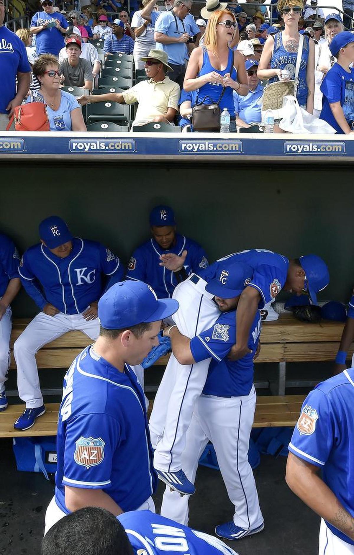 Royals third baseman Mike Moustakas picks up teammate Terrance Gore in the dugout before a 2016 spring training game in Surprise, Ariz.