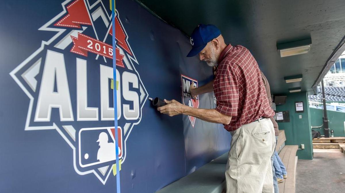
Bob Huggins installs the American League Division Series signs in the Royals dugout on Tuesday, Oct. 6, 2015, at Kauffman Stadium two days before Game 1 of the series begins.
