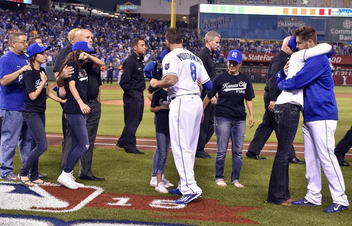 Kansas City Royals third baseman Mike Moustakas (8) and catcher Drew Butera hugged members of the families of fallen firefighters Larry J. Leggio and John V. Mesh after a ceremony to honor their loved ones before Wednesday’s ALDS baseball game on October 14, 2015 at Kauffman Stadium in Kansas City, Mo. Leggio and Mesh both died while fighting a fire Monday night.