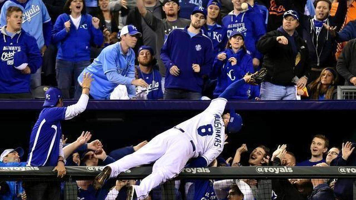 FILE: Kansas City Royals third baseman Mike Moustakas dives for a foul ball hit by Baltimore Orioles center fielder Adam Jones in the sixth inning at Tuesday’s ALCS playoff baseball game on October 14, 2014, at Kauffman Stadium in Kansas City, MO. Moustakas made the catch and landed in the dugout suites.
