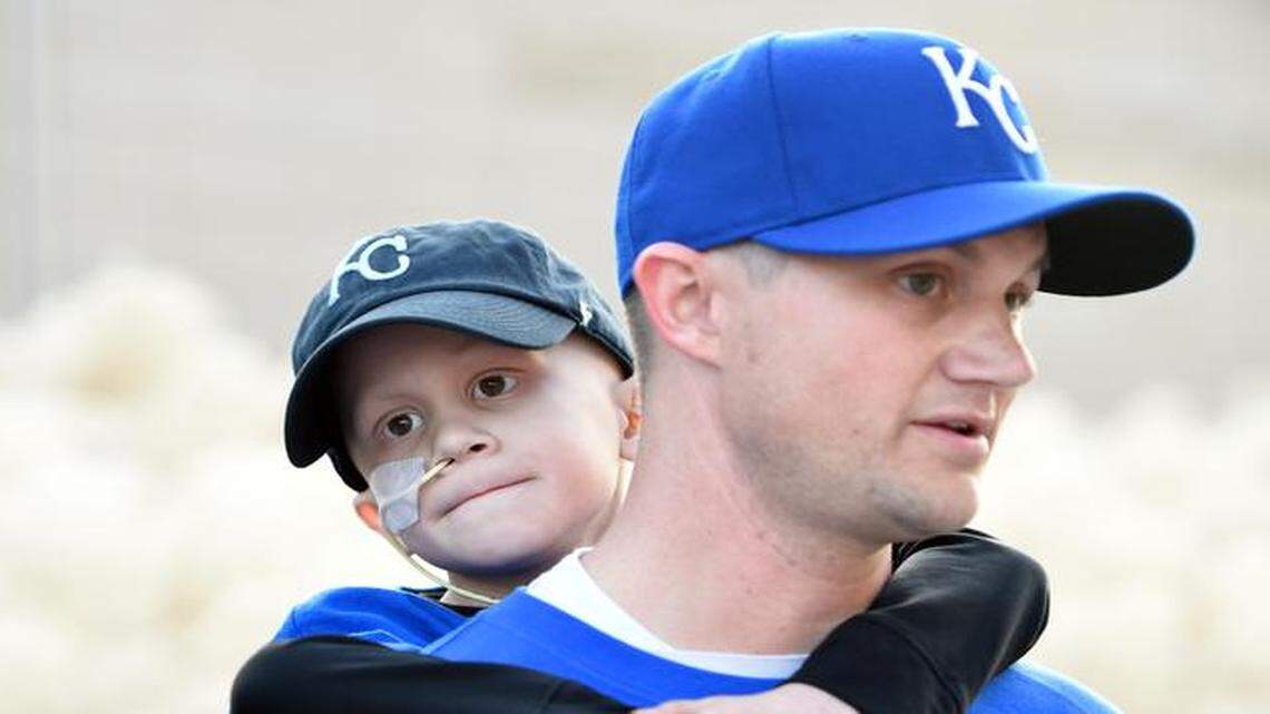 
Noah Wilson, who has a rare form of bone cancer, clung to his father, Scott Wilson of Olathe, before the World Series game Wednesday.
