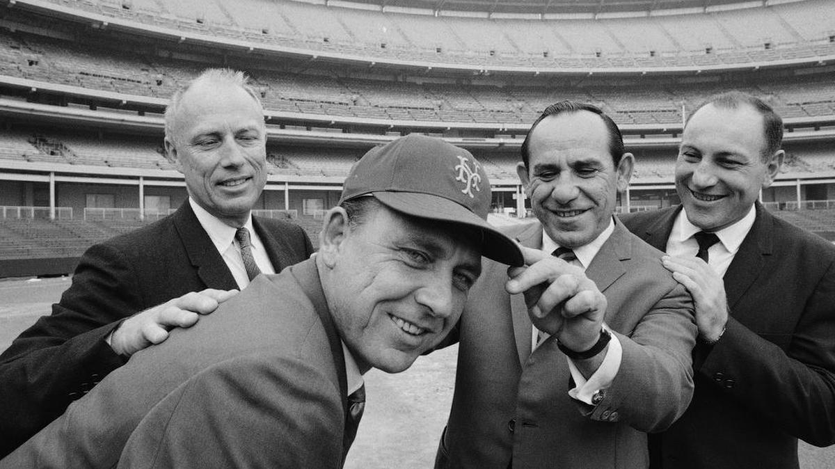 Gil Hodges, the new New York Mets manager, wears a team cap with an added touch by coach Yogi Berra during a visit to Shea Stadium Oct. 17, 1967 in New York. Flanking the two men are Bing Devine, left, president of the team, and Joe Pignatano,right, who’s just been signed on as a coach. Hodges said Berra would continue as the first base coach and Pignatano will serve in the bullpen. (AP Photo)