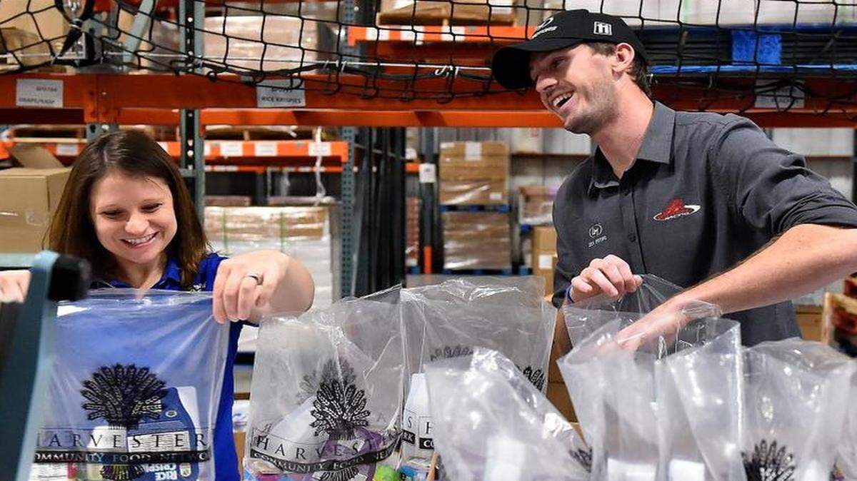 
NASCAR Camping World Truck Series driver Ben Kennedy (right) assisted Kansas Speedway employees, including Lori Hankins, on Tuesday as they filled bags for the back snack program at Harvesters.
