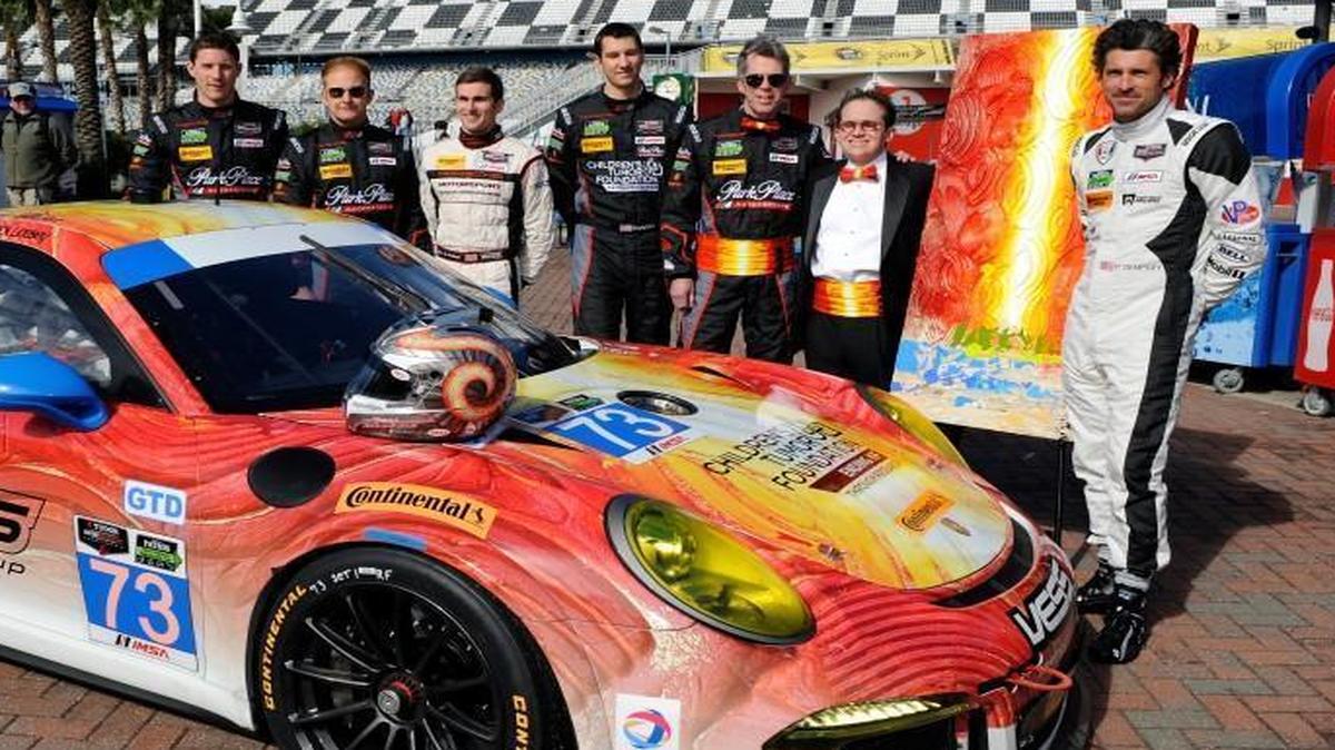 
Jeff Hanson (second from right) posed with actor Patrick Dempsey (right) by a Porsche 911 GT America with Hanson’s artwork on it at the 2014 Rolex 24.

