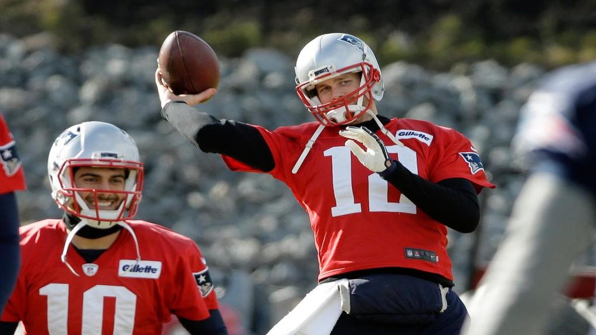 New England Patriots quarterback Tom Brady (12) winds up to throw the ball as quarterback Jimmy Garoppolo (10) stretches during practice on Thursday in Foxborough, Mass.