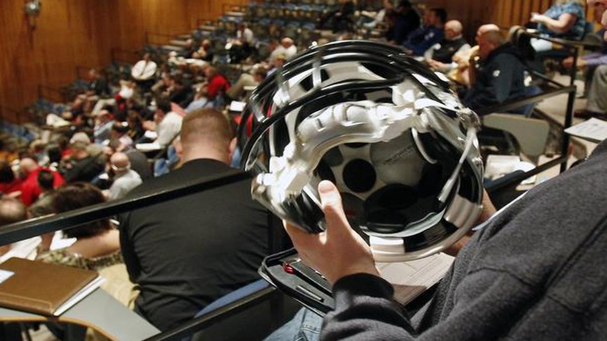 A high school football coach examined a new helmet at a 2011 safety seminar in the Kansas City area.