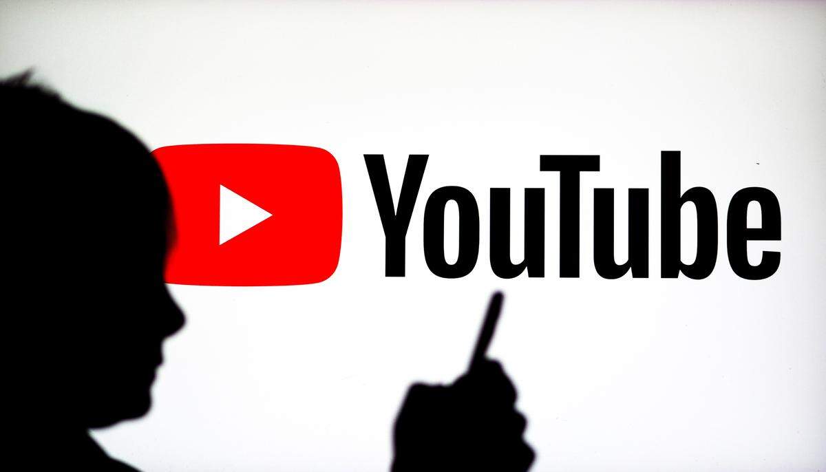In this photo illustration, a Youtube logo seen on display with a child watching something on his phone.
