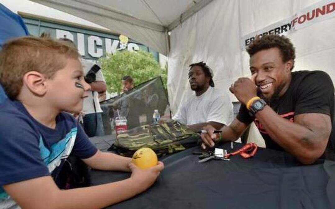 
Eric Berry, a safety with the Kansas City Chiefs, laughs with 5-year-old Andre Smith on Friday at Bolger Square in front of Dick's Sporting Goods in Independence. The Eric Berry Foundation hosted the 500 Backpacks Giveaway event. Children were not only able to pick up backpacks filled with school supplies, they could play games and chow down at the event.
