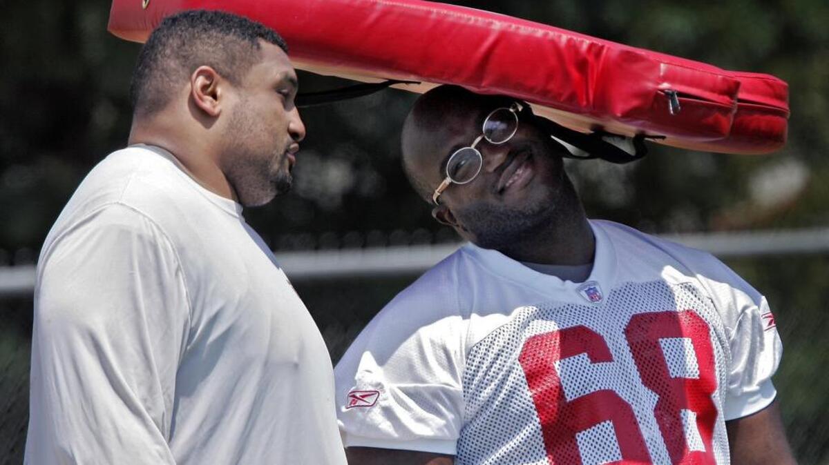 FILE: As he chatted with Willie Roaf (left), Will Shields (right) beat the heat Monday with the help of a practice pad. The two offensive linemen rested and didn’t take part in the Chiefs’ practice.