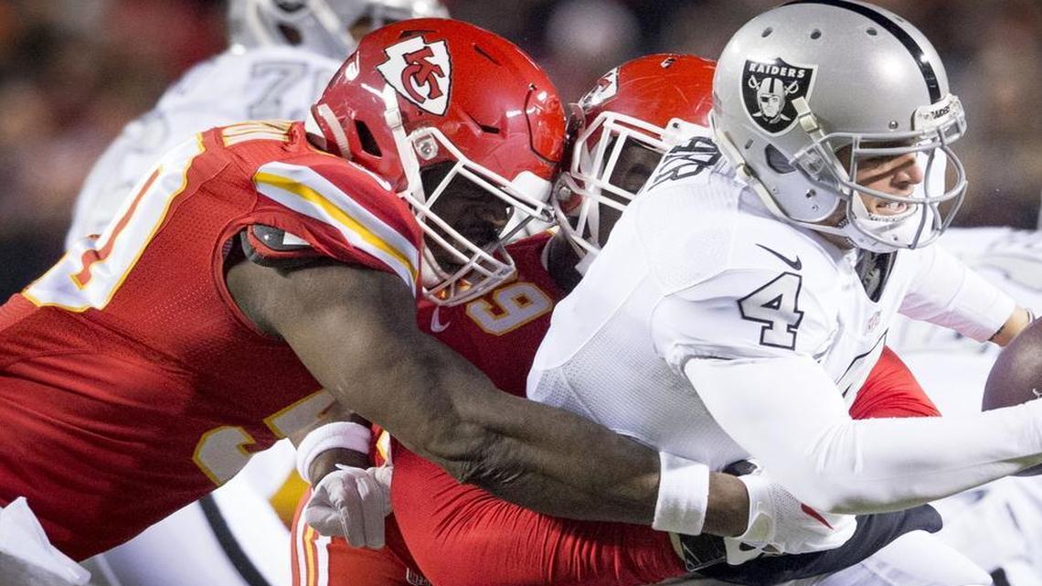 Kansas City Chiefs outside linebacker Justin Houston (50) and Kansas City Chiefs defensive tackle Kendall Reyes (98) sacked Oakland Raiders quarterback Derek Carr (4) in the first quarter during the Kansas City Chiefs and Oakland Raiders football game at Arrowhead Stadium on Thursday, December 8, 2016.