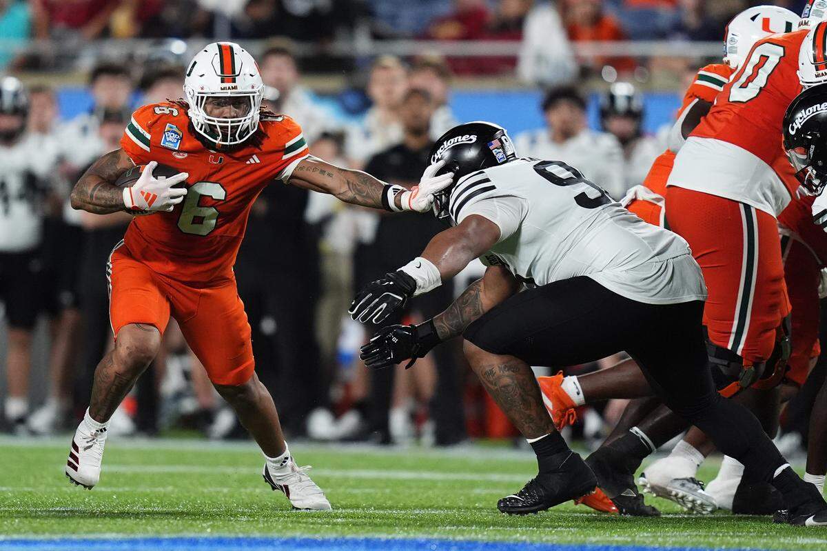 Miami Hurricanes running back Damien Martinez (6) stiff arms Iowa State Cyclones linebacker Cael Brezina (9) during the second half on Dec. 28, 2024, at Camping World Stadium in Orlando, Florida.