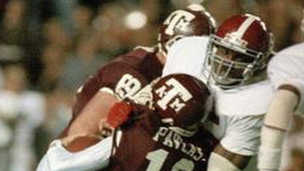 
Texas A&M quarterback Lance Pavlas (12) is sacked for a 4-yard loss by Derrick Thomas (55) of the Alabama Crimson Tide, Dec. 1, 1988. The action is from the first period of the game, dubbed the “Hurricane Bowl” at College Station, Texas.
