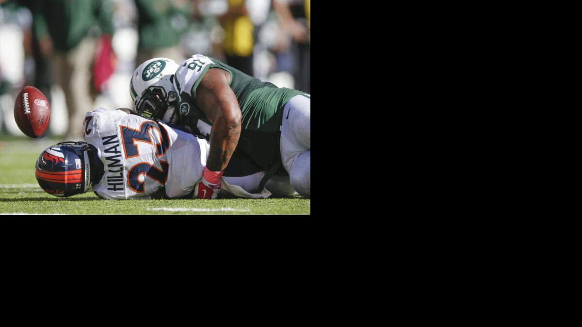 Denver Broncos running back Ronnie Hillman (23) fumbles the ball as he is tackled by New York Jets defensive end Sheldon Richardson (91) during the third quarter of an NFL football game, Sunday, Oct. 12, 2014, in East Rutherford, N.J. The Broncos recovered the ball on the play.