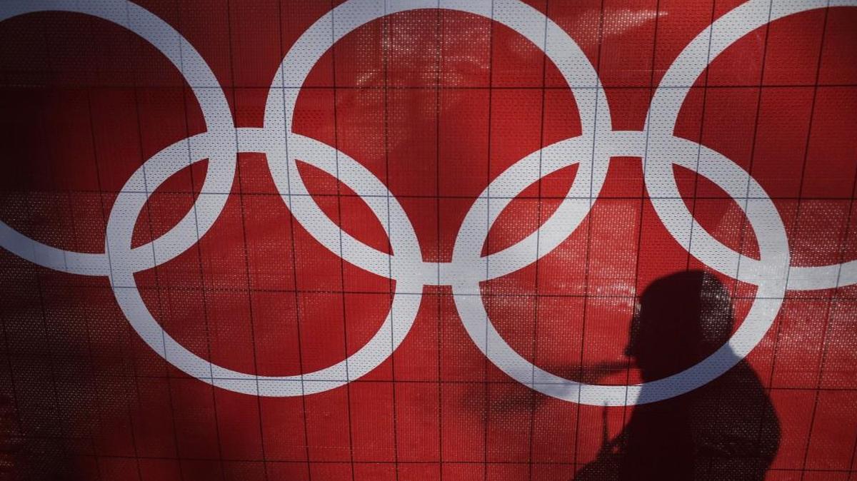 In this Feb. 15, 2014 file photo the shadow of a man is cast on the Olympic rings as he smokes at the Rosa Khutor Alpine Center, at the 2014 Winter Olympics in Krasnaya Polyana, Russia.