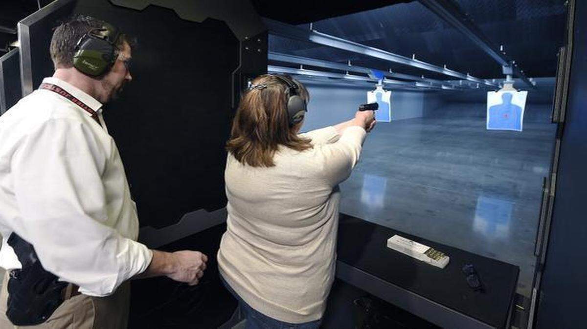 
Co-owner Mike Brown watched as Sarah Brown from Grandview, who is not related to the owners, tried out a handgun recently at the indoor range before buying one at Frontier Justice in Lee’s Summit.
