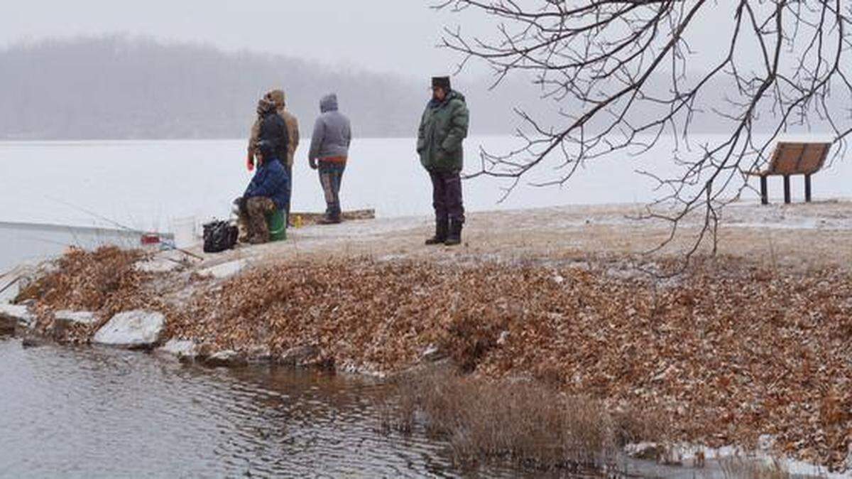 Fishermen huddled against the cold Saturday as they fished off a point on Shawnee Mission Lake during the Johnson County trout opener.