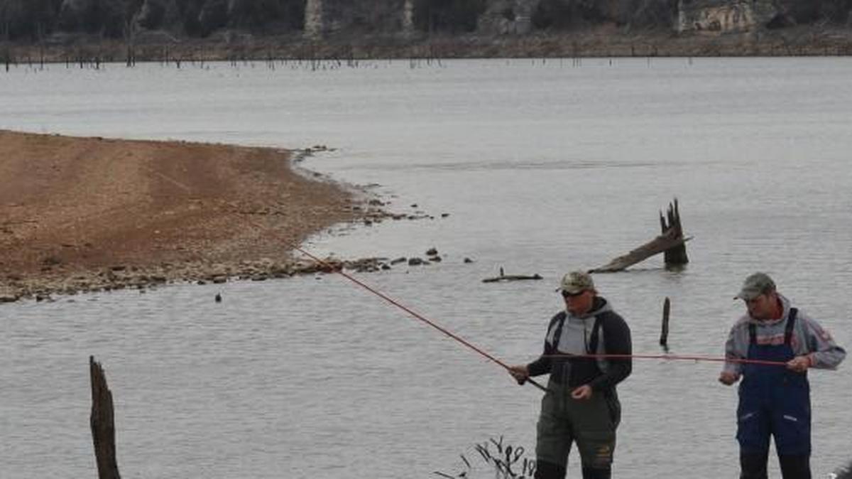 Guide Richard Bowling (left) and Larry Chambers used long poles to dip the brush for crappies in a cut at Truman Lake.