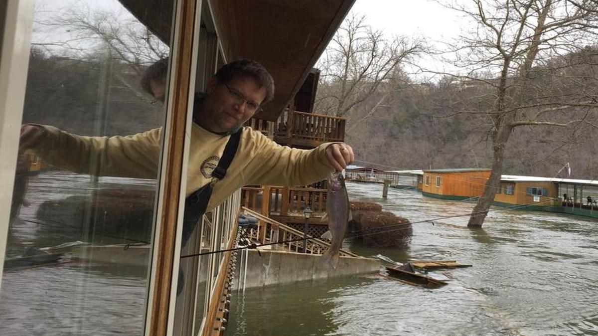 Phil Lilley, of Lilleys’ Landing Resort and Marina in Branson, shows off a rainbow trout he caught out the window of the sun room in his home.