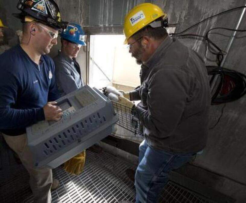 
Urban wildlife biologist Joe DeBold of the Missouri Department of Conservation held the carrier as wildlife resource technician Jeff Goin placed the peregrine falcon chicks back in the nesting box after banding on June 16, 2014, at the KCP&L Iatan Generation Station.
