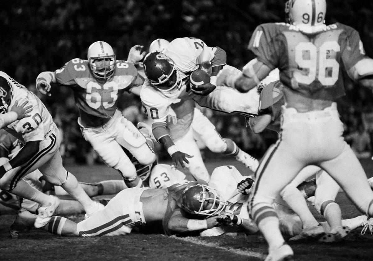 In this Jan. 1, 1979, file photo, Oklahoma's Billy Sims (20) scores a touchdown against Nebraska during the Orange Bowl in Miami. Pursuing is Nebraska's Dave Clark (63).
