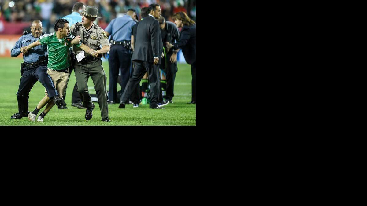 
Police and security officers restrain fans that ran onto the playing field at the end of the exhibition soccer match between Mexico and Paraguay on March 31, 2015 at Arrowhead Stadium in Kansas City, Mo. Mexico won, 1-0.
