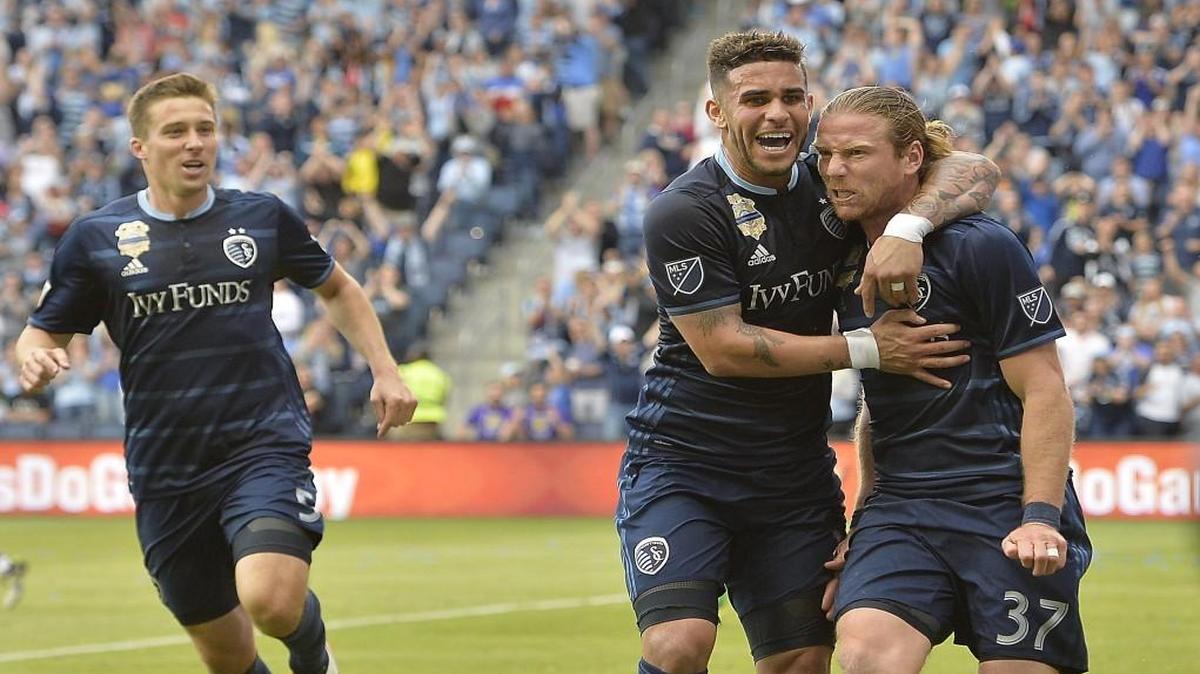 As Sporting Kansas City's Matt Besler (5) runs toward them, Dom Dwyer (center) and Jacob Peterson (37) celebrate Peterson's goal.