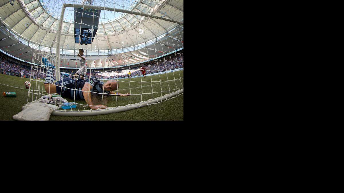 
Sporting Kansas City’s Aurelien Collin (bottom) fell into the back of the goal after making a save when goalkeeper Andy Gruenebaum (right) was caught out of position in the first half. The Vancouver Whitecaps won the match 2-0.
