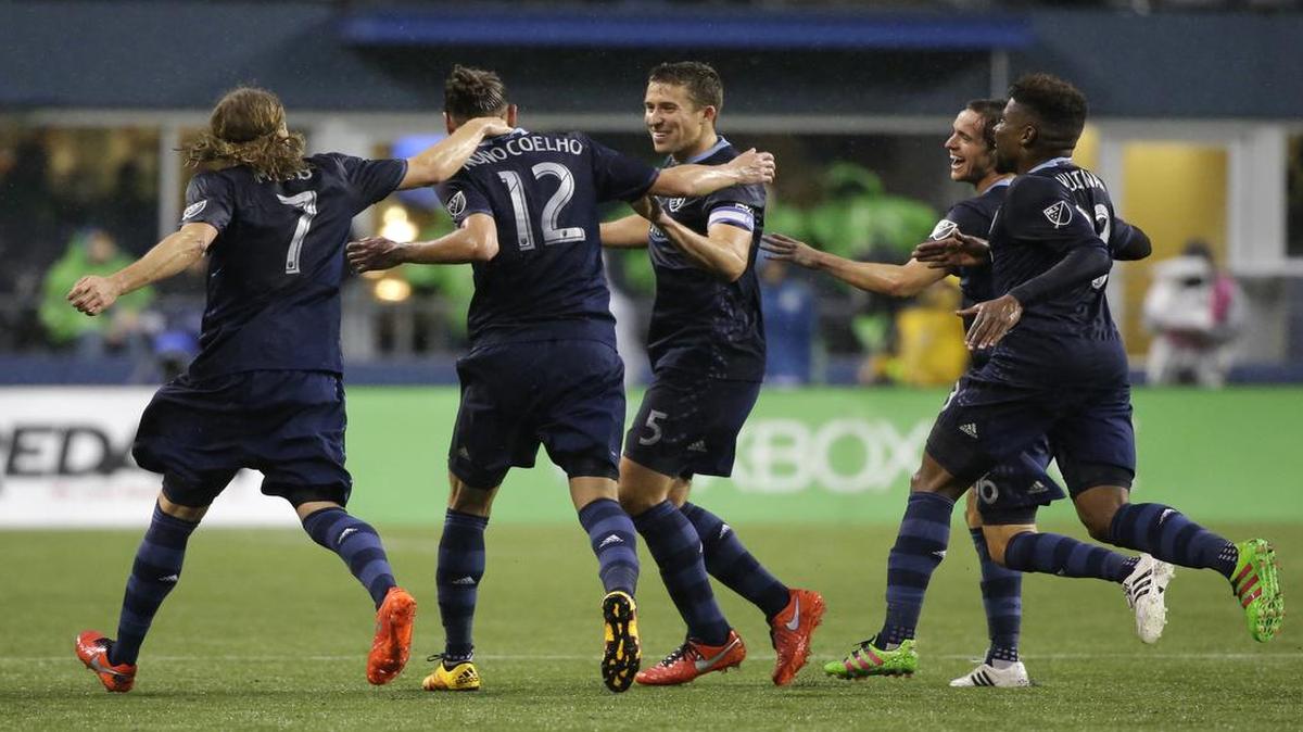 Teammates, including Chance Myers (7) and Matt Besler (5) greet Sporting Kansas City defender Nuno Coelho (12) after Coelho kicked a goal against the Seattle Sounders in the second half of an MLS soccer match, Sunday, March 6, 2016, in Seattle. Sporting Kansas City beat the Sounders 1-0.