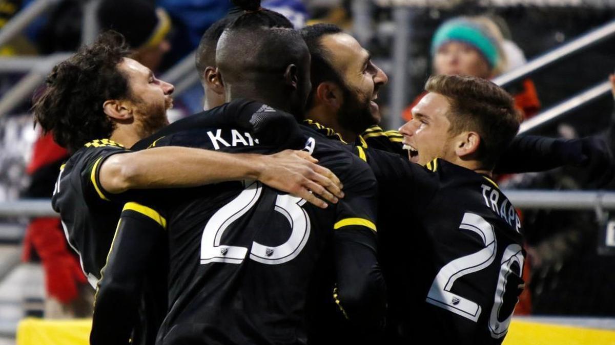 Columbus Crew teammates including Kei Kamara (23) surround Justin Meram (second from right) after Meram’s quick-strike goal Sunday against the Red Bulls.
