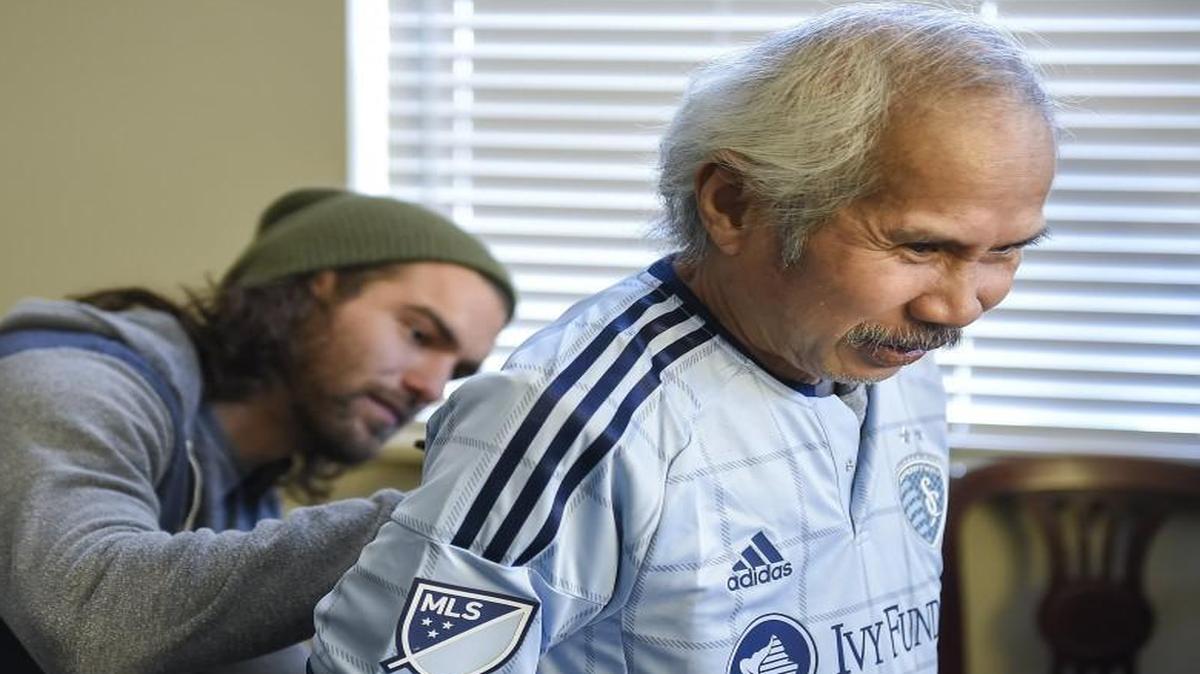 Thephayonh "Lee" Promsenmuong, right, a resident of the Rehabilitation Center of Independence hospice center and a passionate fan of Sporting Kansas City, smiled as he received an autograph on the back of his jersey from Sporting midfielder Graham Zusi.