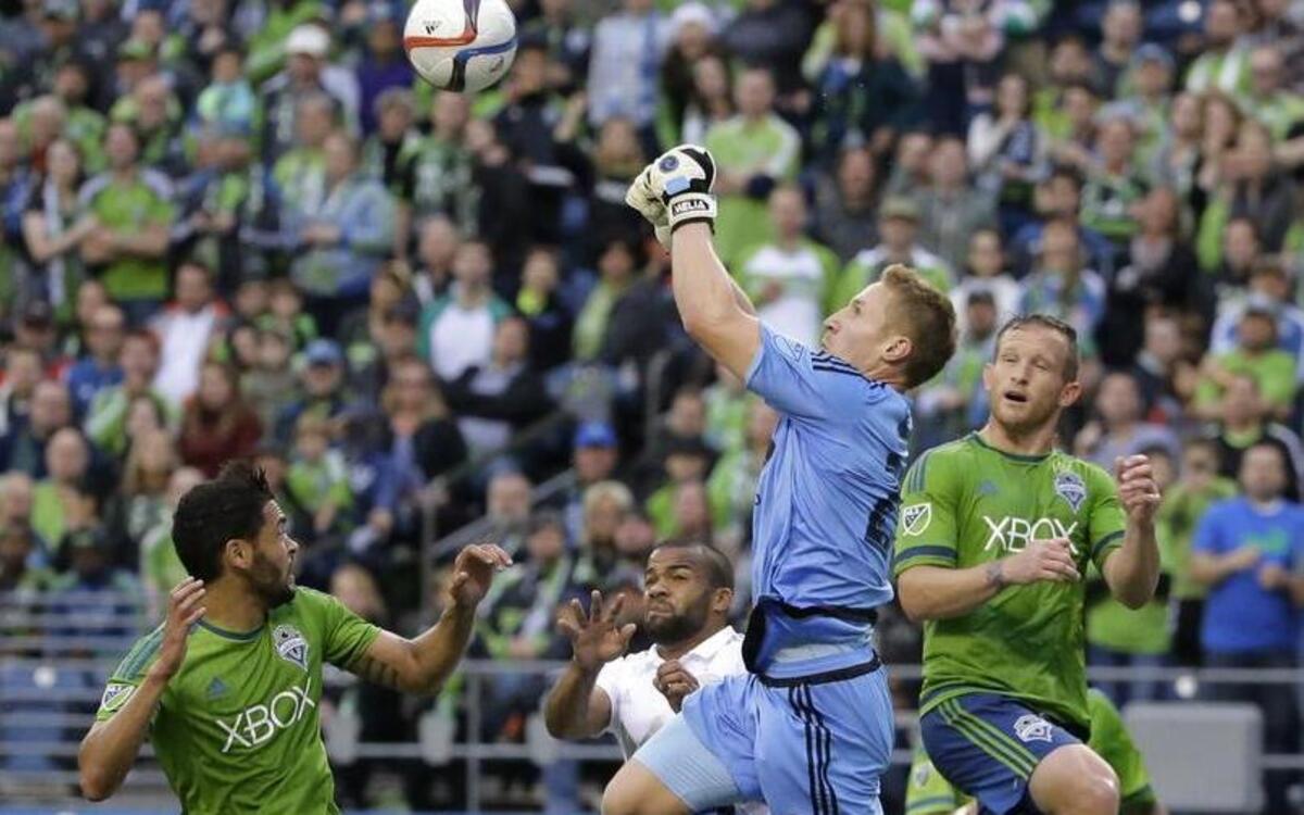 
Sporting Kansas City goalkeeper Tim Melia leaped above teammate Kevin Ellis to punch the ball away from Seattle’s Chad Barrett (right) and Lamar Neagle during a game last month in Seattle.

