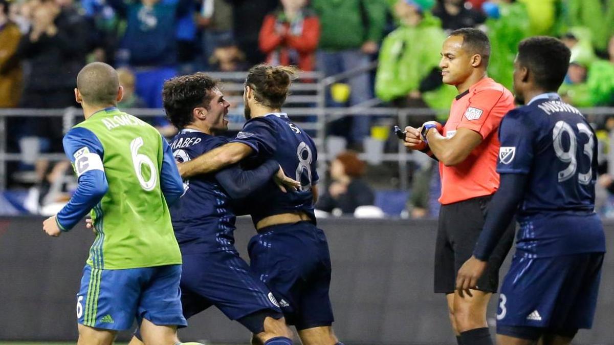 Sporting Kansas City midfielder Benny Feilhaber, second from left, is restrained by Graham Zusi (8) as he protests to referee Ismail Elfath, second from right, after a play involving Seattle Sounders midfielder Osvaldo Alonso, left, in the second half of an MLS soccer playoff matchon Oct. 27, 2016, in Seattle. Feilhaber was given a yellow card for dissent on the play. The Sounders beat Sporting Kansas City 1-0.