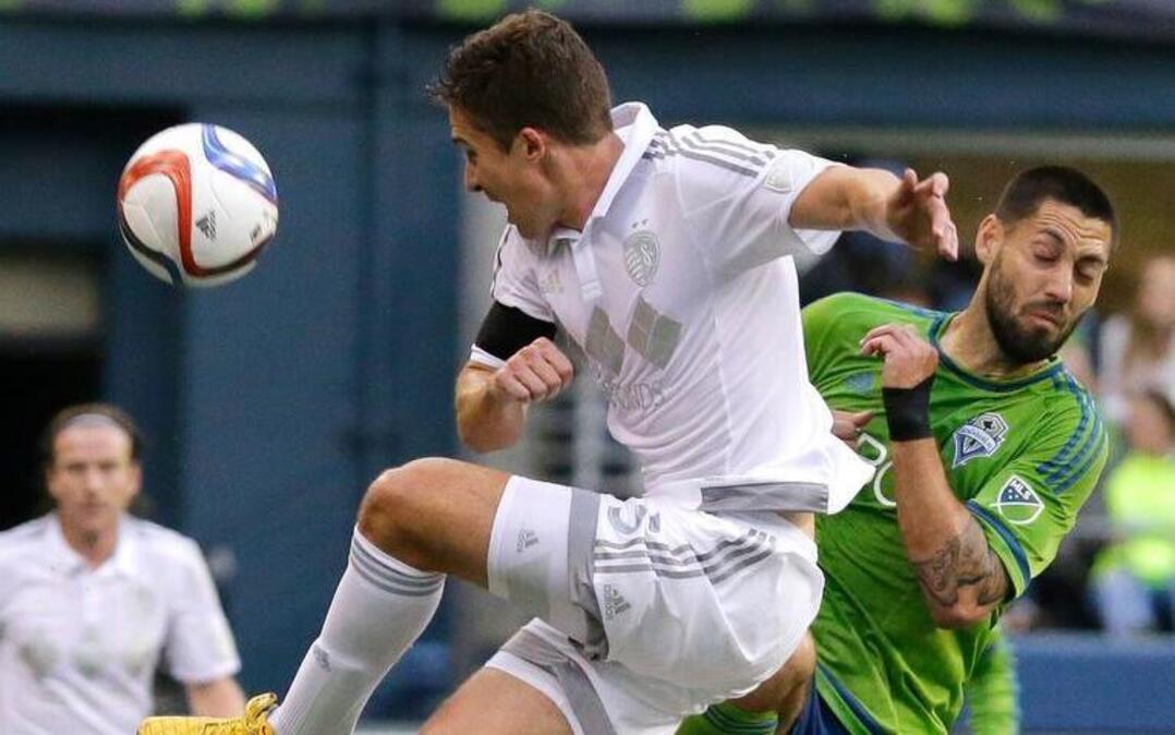 
Sporting Kansas City’s Matt Besler (front left) leapt to kick the ball away from the Seattle Sounders’ Clint Dempsey (right) in the first half Saturday night in Seattle. The match ended in a scoreless draw.
